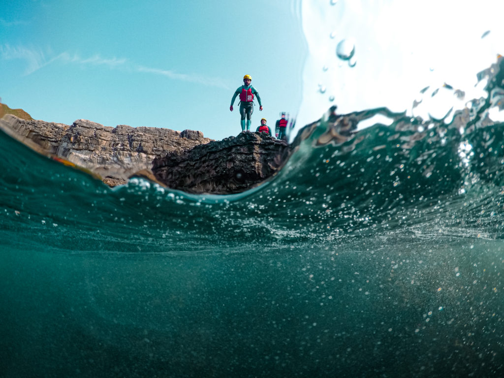 The epic experience of coasteering in Dorset. Man preparing to jump into the water whilst the camera is under water