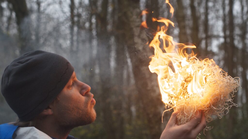 Man creating fire by blowing air into kindling at Nordon locations