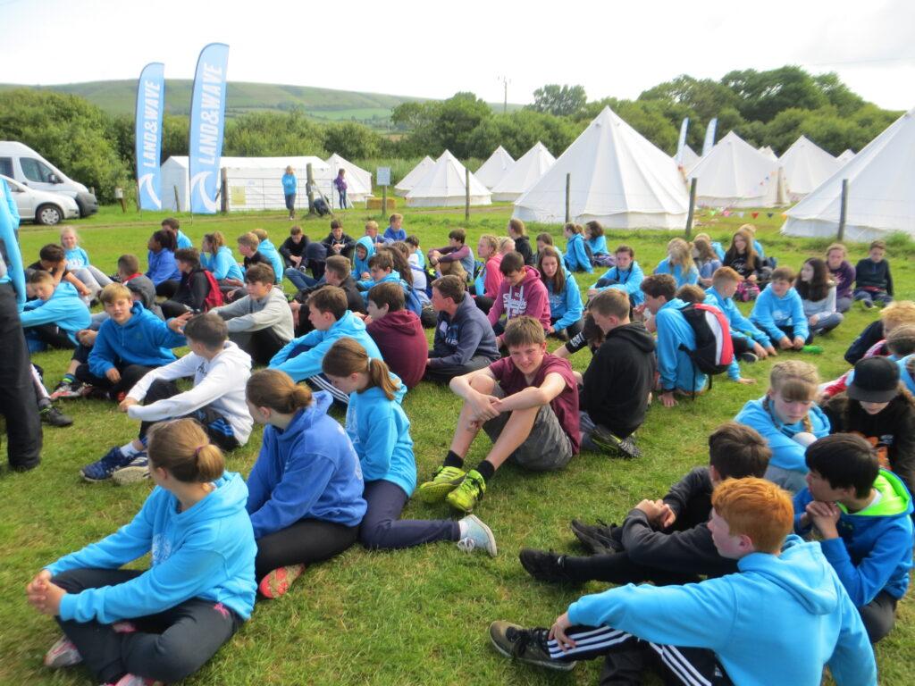 Children sat down with the tents in the back ground
