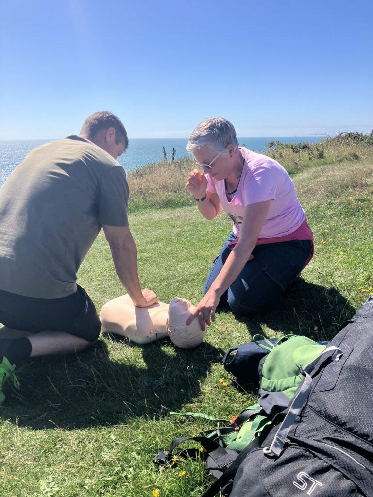 two people are knelt down next to a CPR dummy